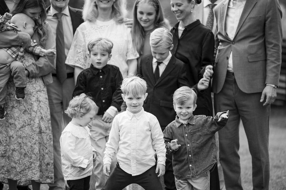 Black and white photo of children smiling and playing at a family gathering outdoors.