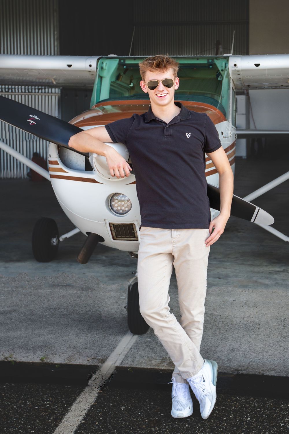 Hartland High school senior guy portrait with Cessna airplane in Howell Michigan; senior photos by South Lyon, MI photographer