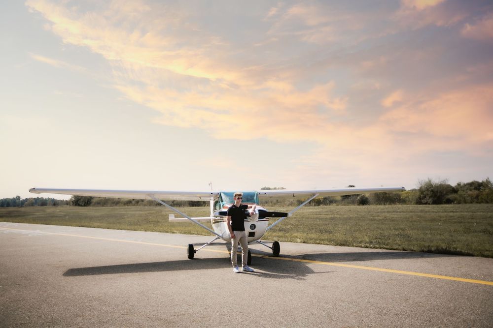 Hartland High school senior guy portrait with Cessna airplane in Howell Michigan; senior photos by South Lyon, MI photographer