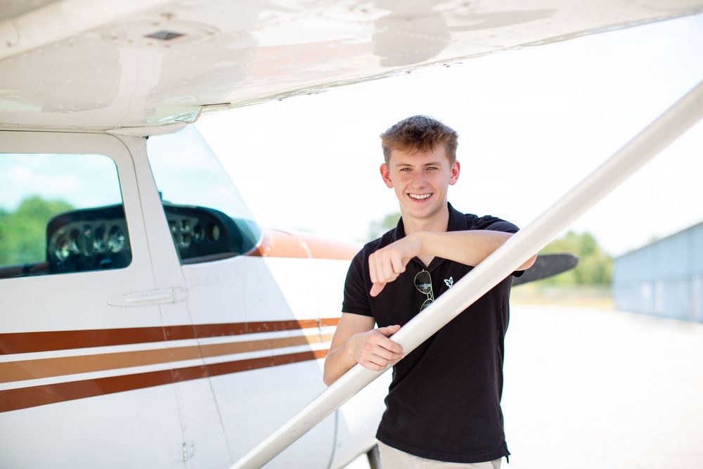 Hartland High school senior guy portrait with Cessna airplane in Howell Michigan; senior photos by South Lyon, MI photographer