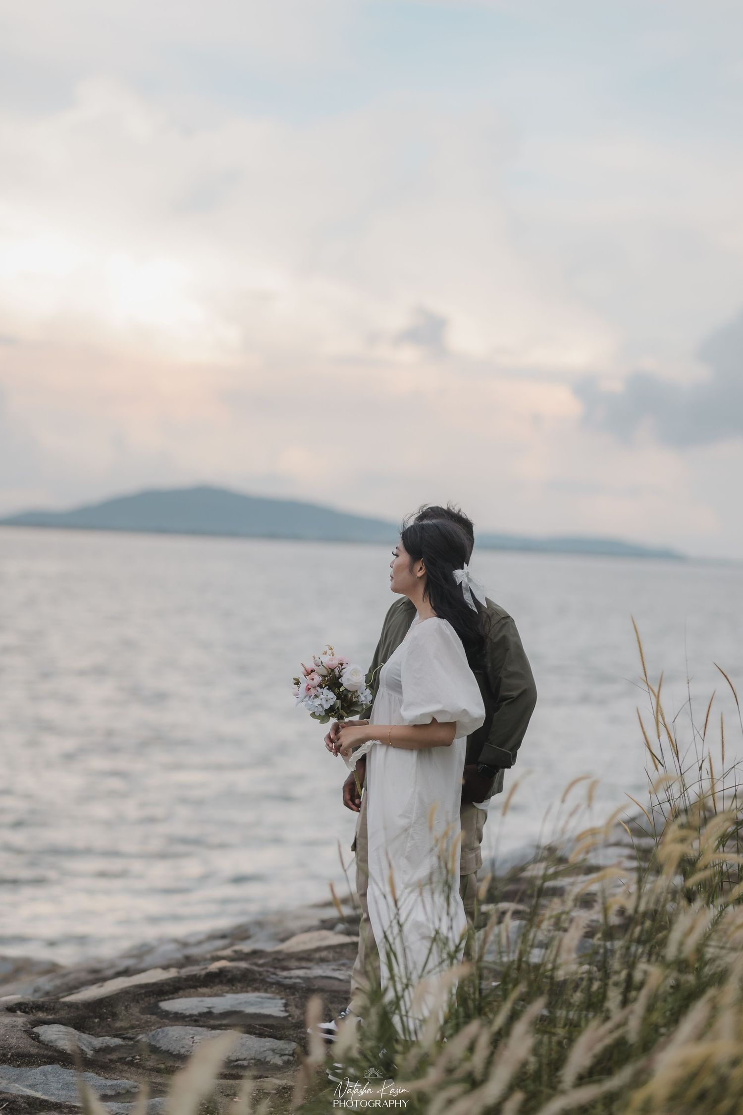 A romantic sunset photoshoot in a grassy field with warm golden light.