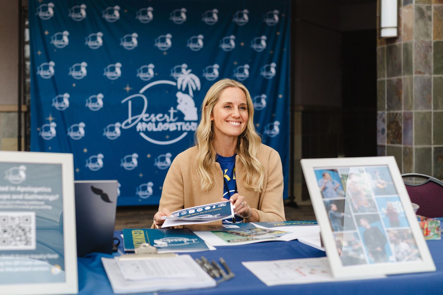 Book signing event setup with branded blue backdrop and display materials on tables.