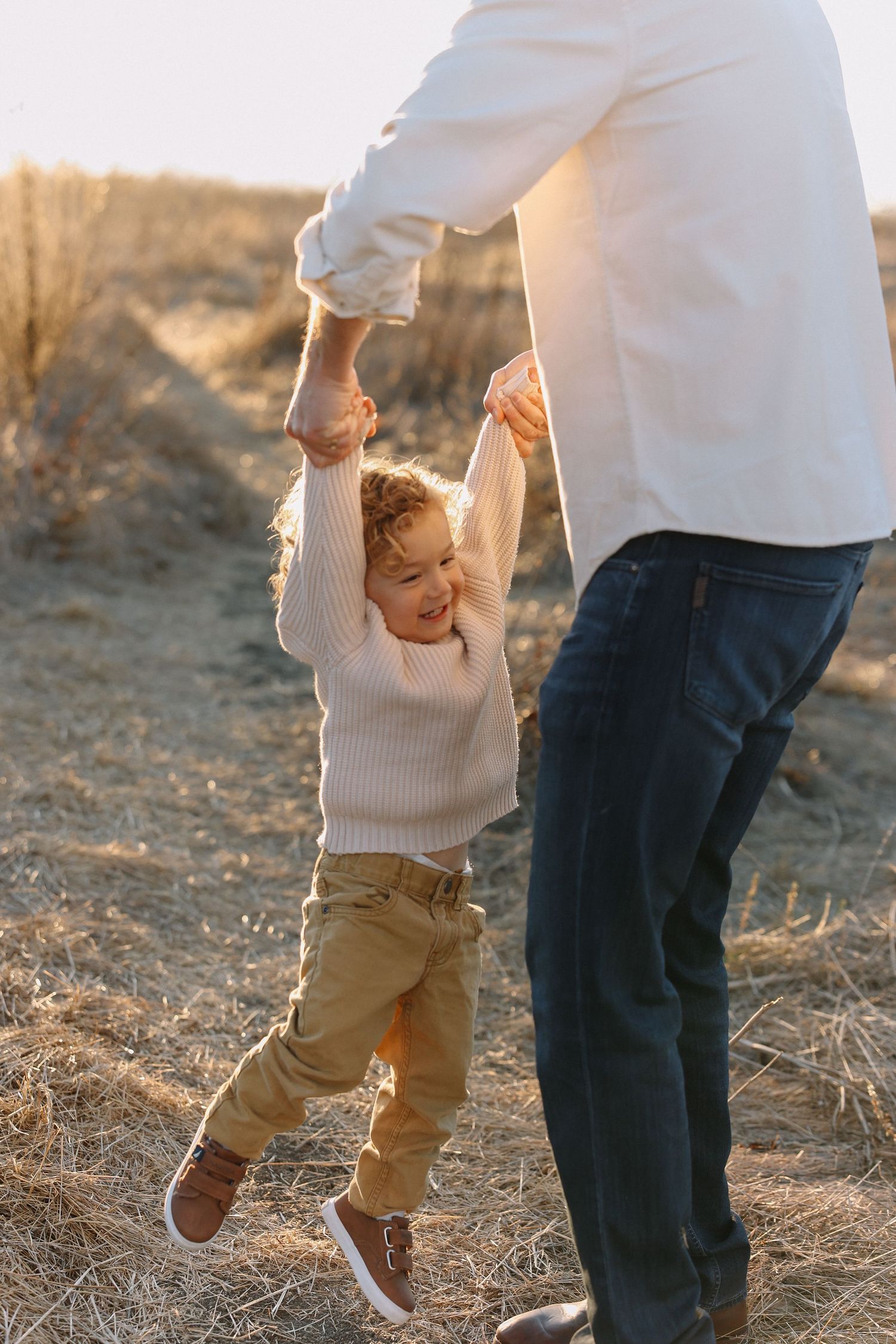 Parent and toddler playing together in a field during golden hour