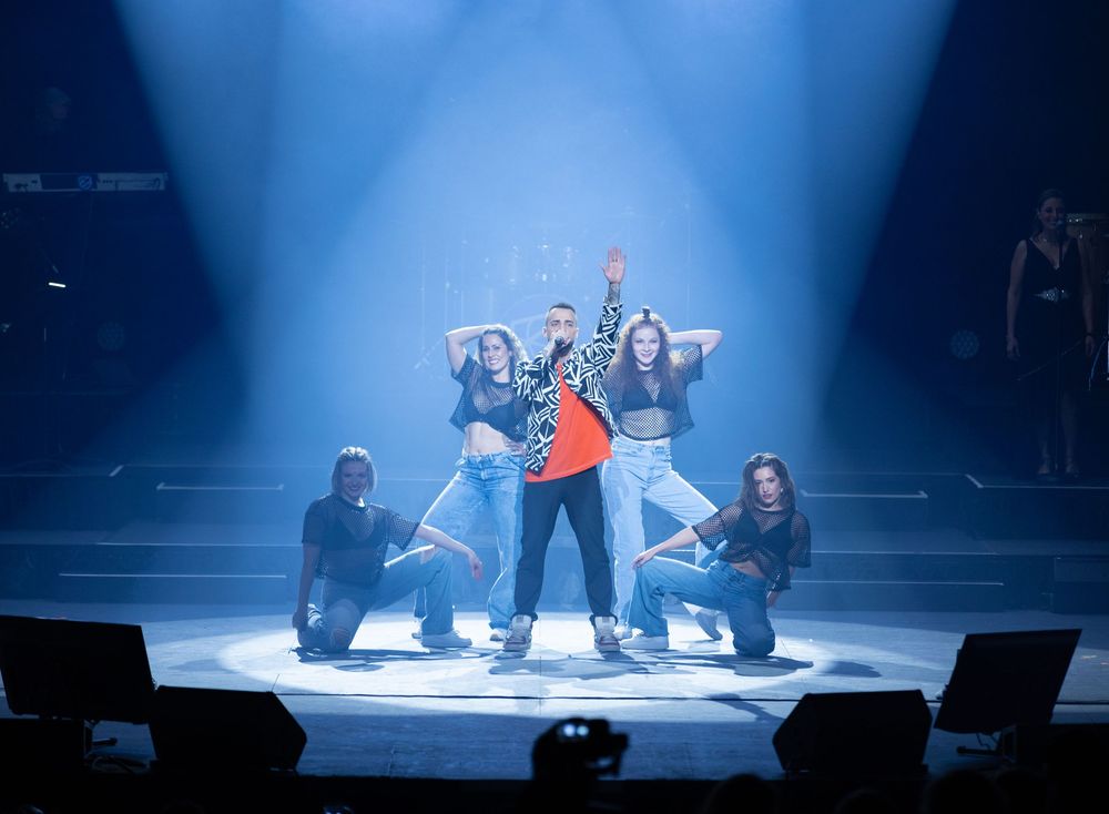 Dynamic dance performance by Diogo Piçarra on stage with blue spotlight and theatrical effects.