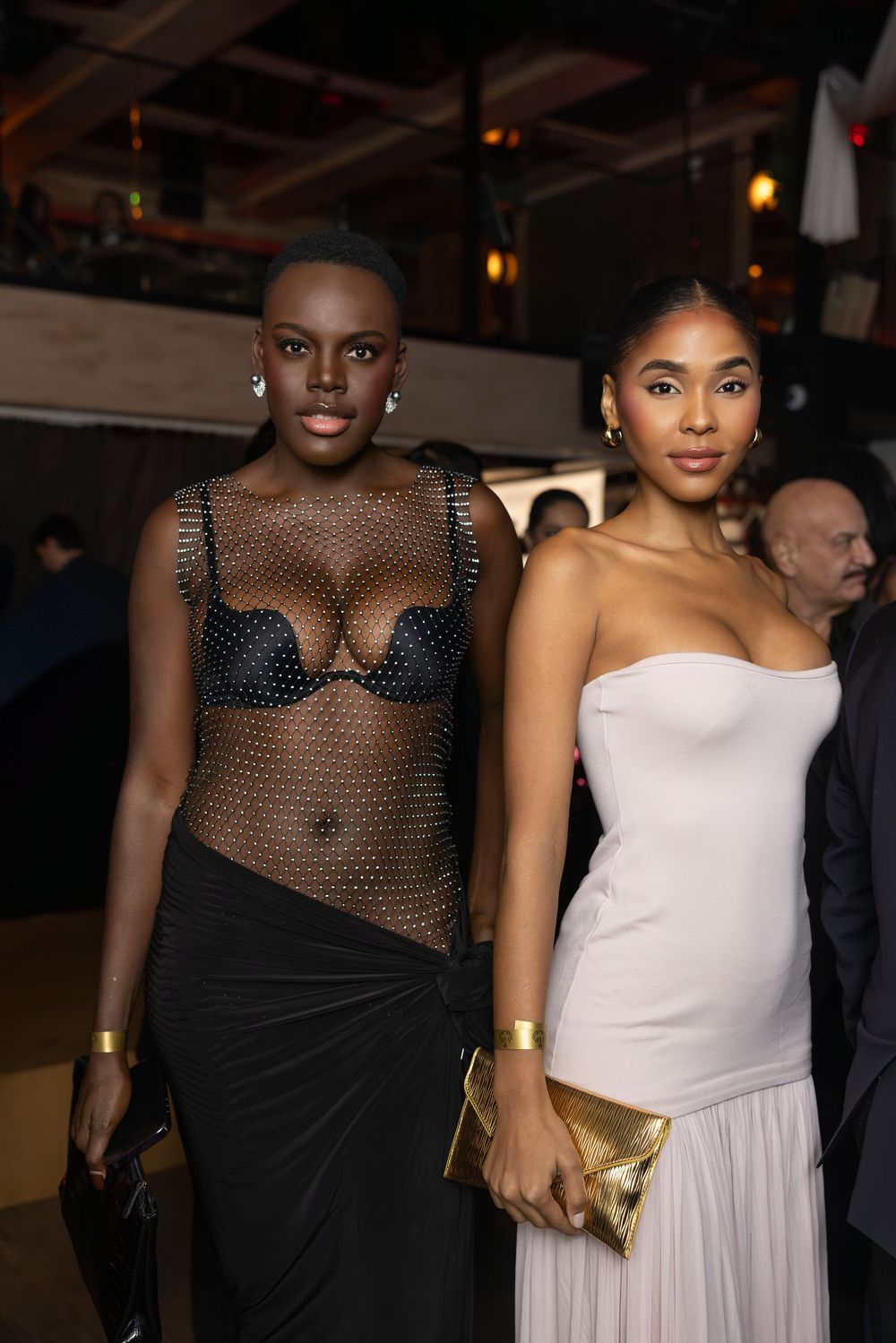 Models walk the runway in contrasting black mesh and white strapless gowns at an evening fashion event.