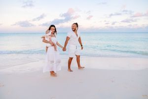 Family enjoying playful moments together on sandy beach.