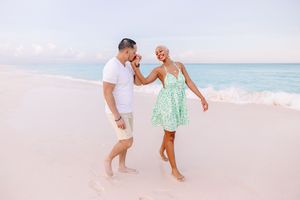 Playful couple running and laughing together on a sunny beach.