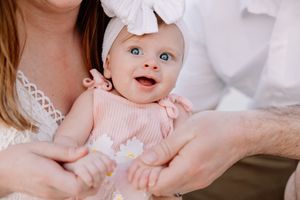 Baby in pink outfit during indoor portrait session.