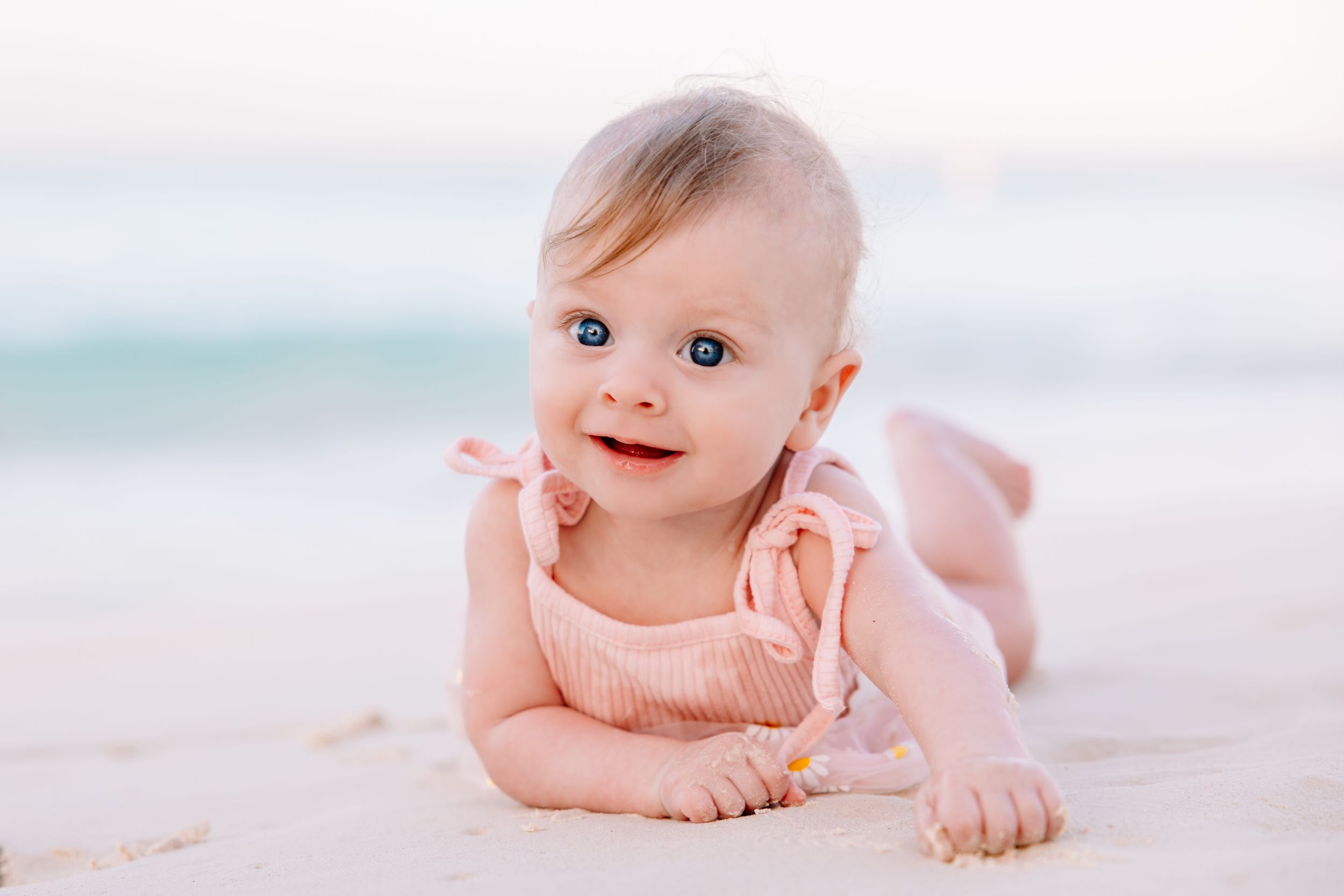 Infant lying on soft white blanket during professional photo session.