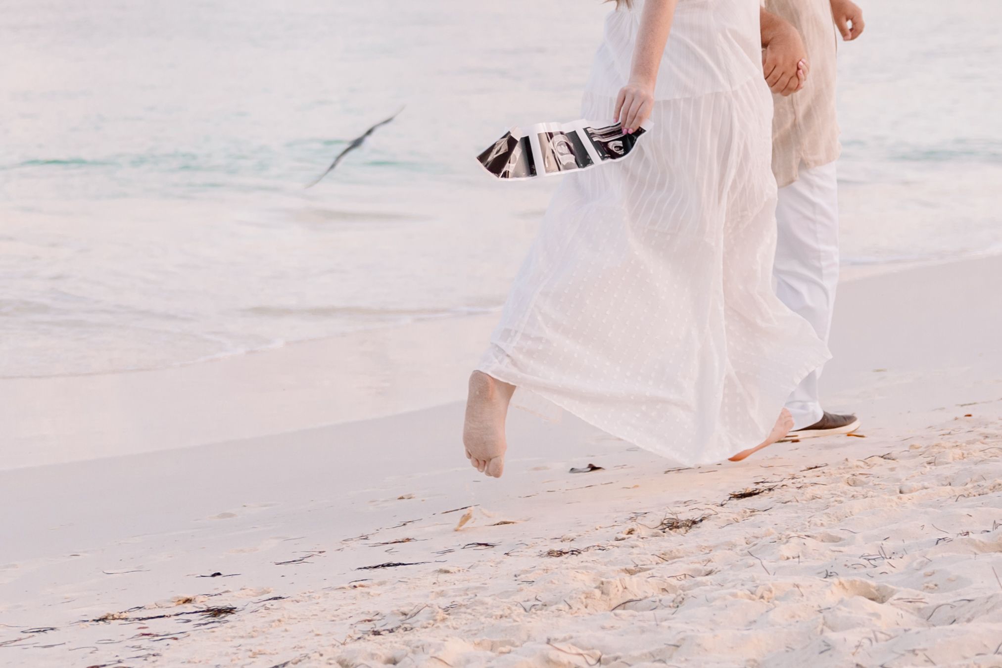 Couple strolling hand in hand on a pristine white sand beach.