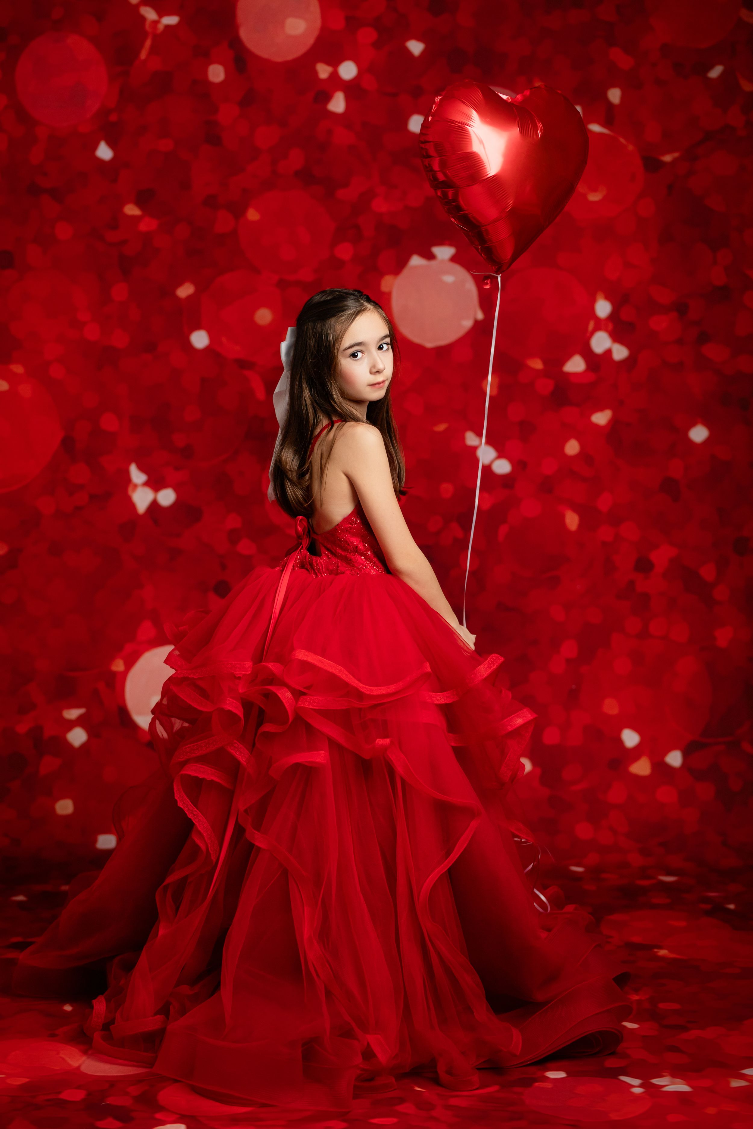 A dramatic portrait against a deep red background with white butterflies features an elegant red ruffled gown.
