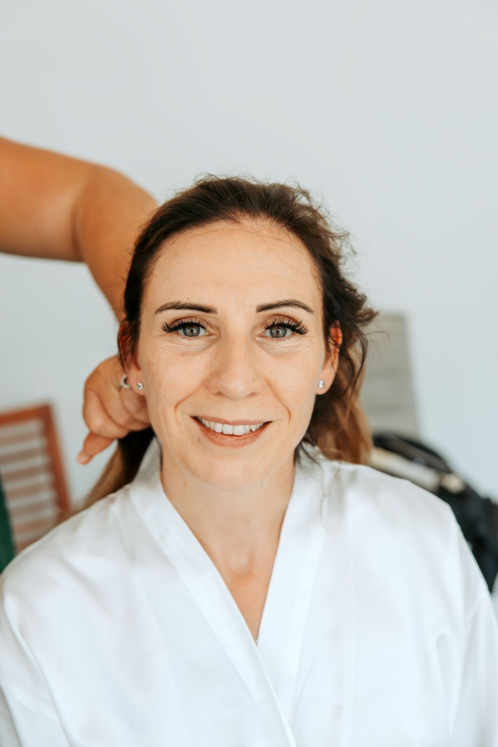 Someone wearing a white robe smiles during wedding preparations.