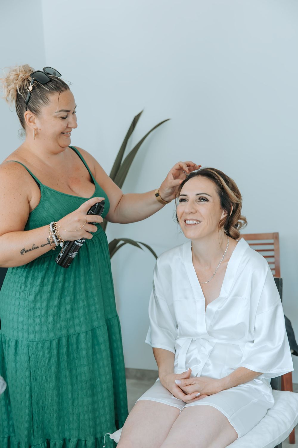 A stylist in green works on hair preparations before a wedding.