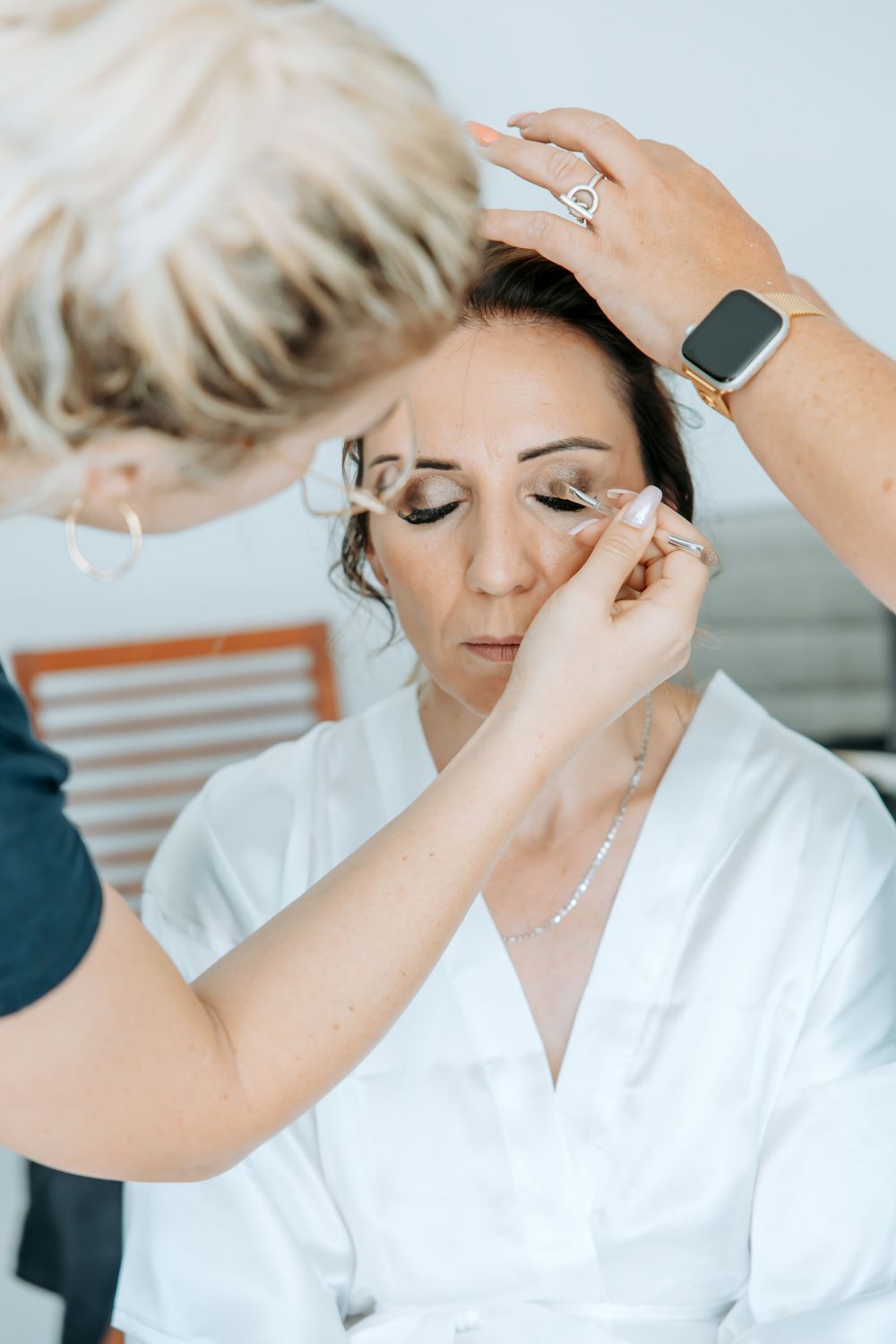 A makeup artist applies cosmetics during wedding preparation.