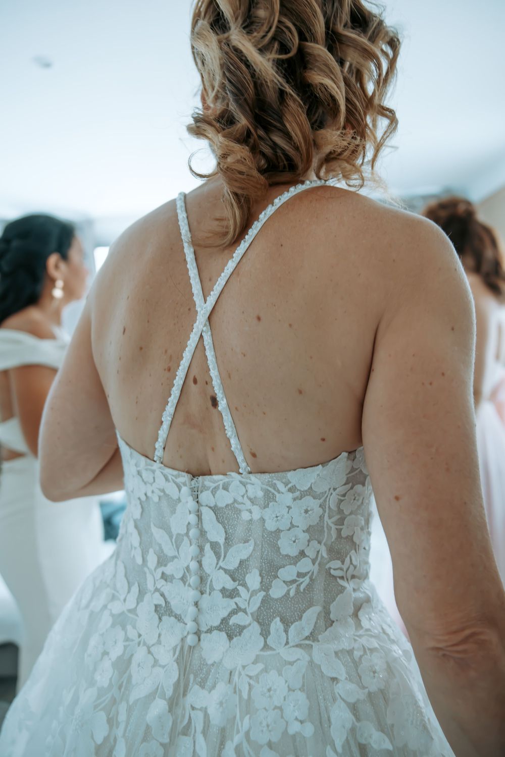 A detailed back view of a white lace wedding dress with crossed straps.