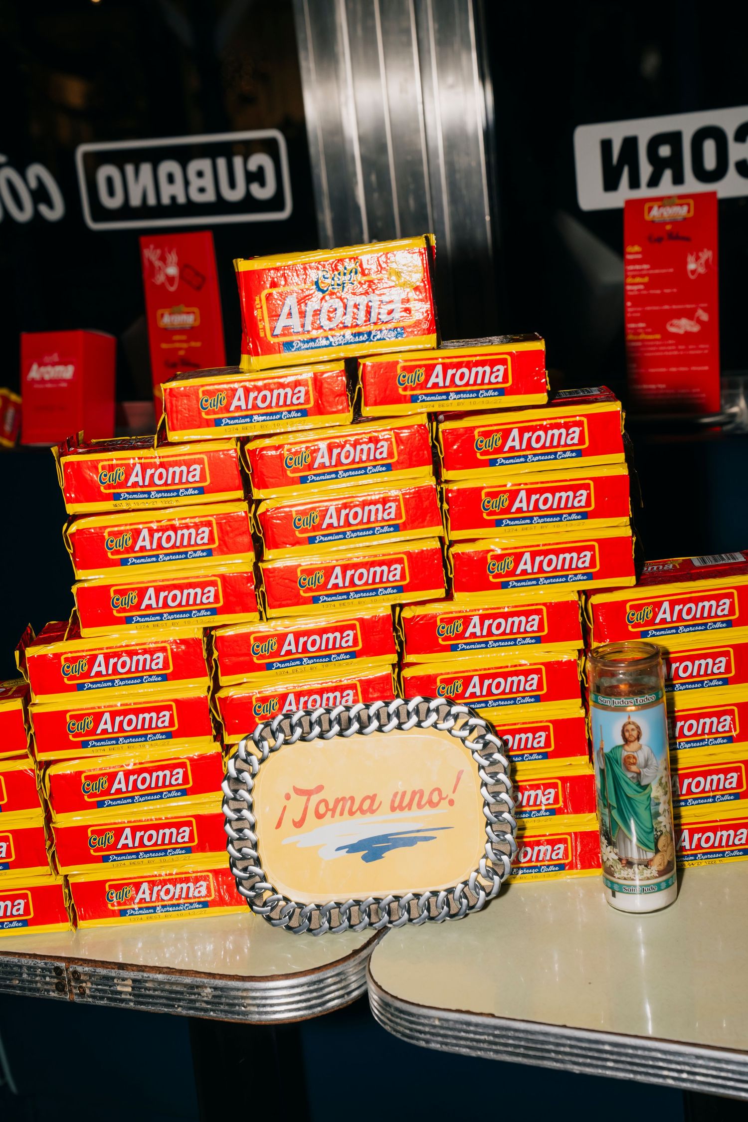 Multiple red Aroma brand boxes arranged on a shelf with silver trays and decorative items in a retail display setting.