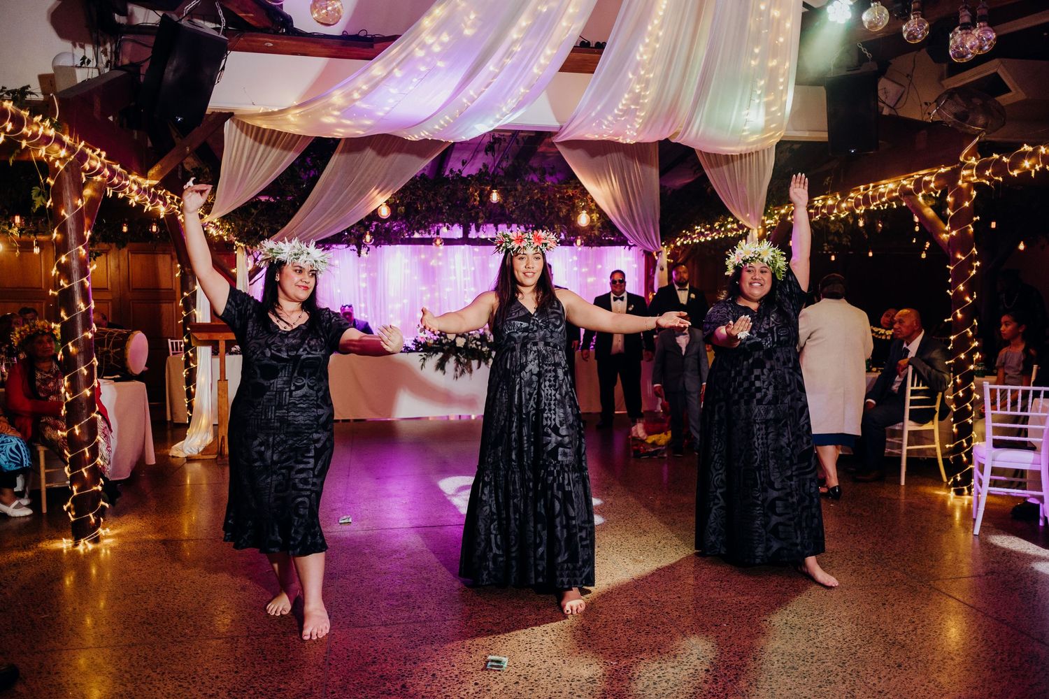 Wedding reception venue with rustic wooden table settings and elegant hanging greenery in an industrial-style space.