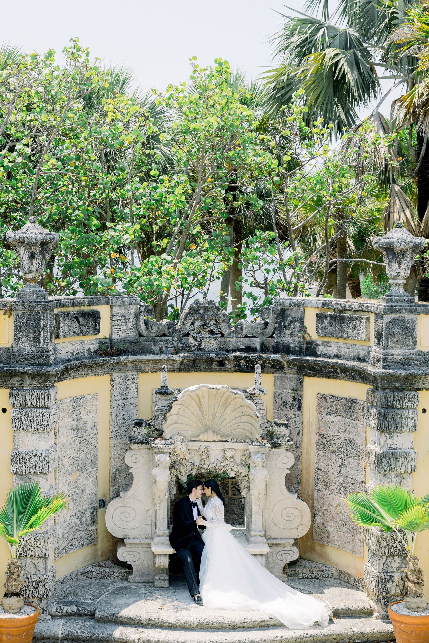 Elegant stone archway and garden at Vizcaya Museum with tropical palm trees and lush green foliage in Miami, Florida.