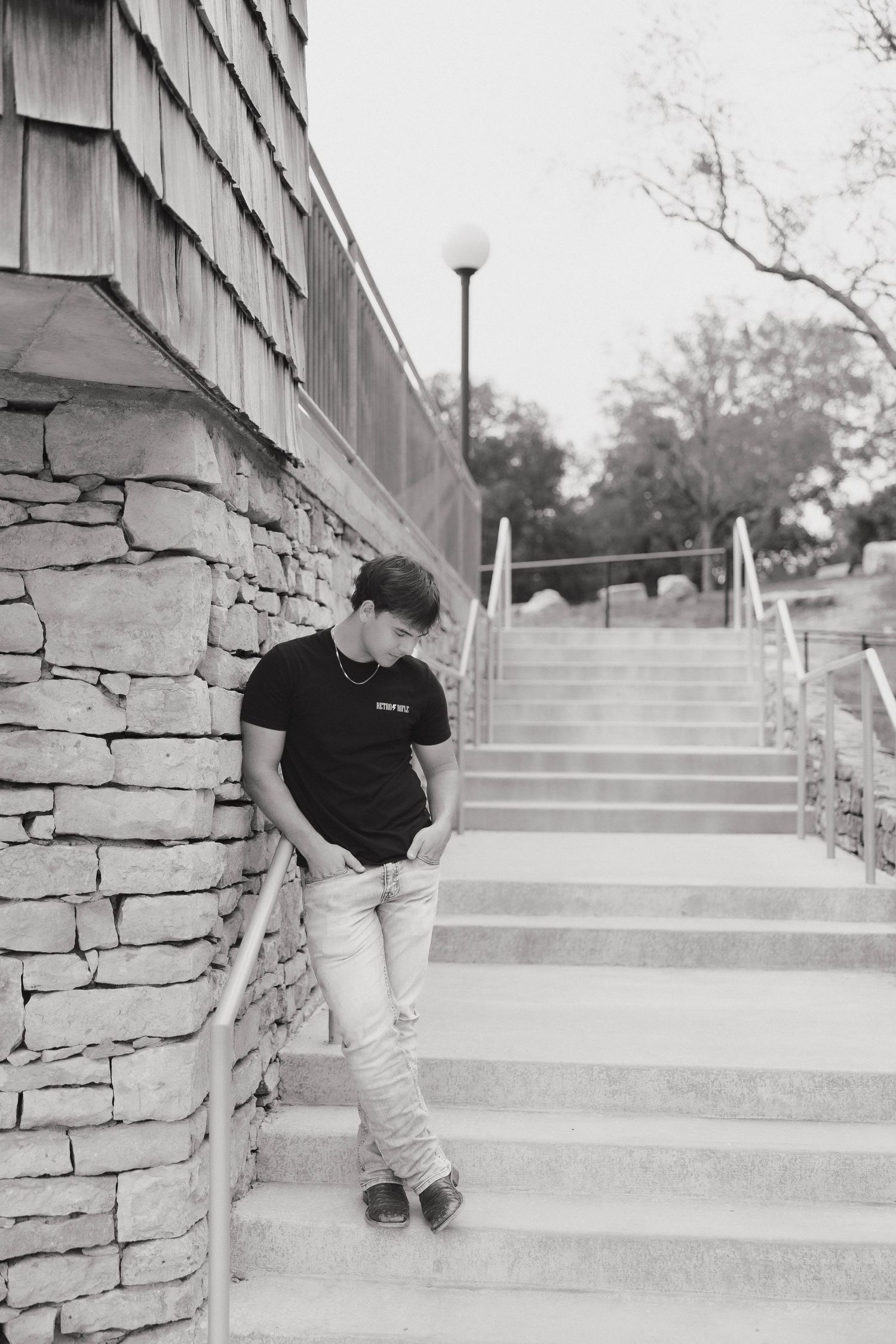 A sequence of black and white photos showing a skateboarder performing a trick on concrete steps near a stone wall.