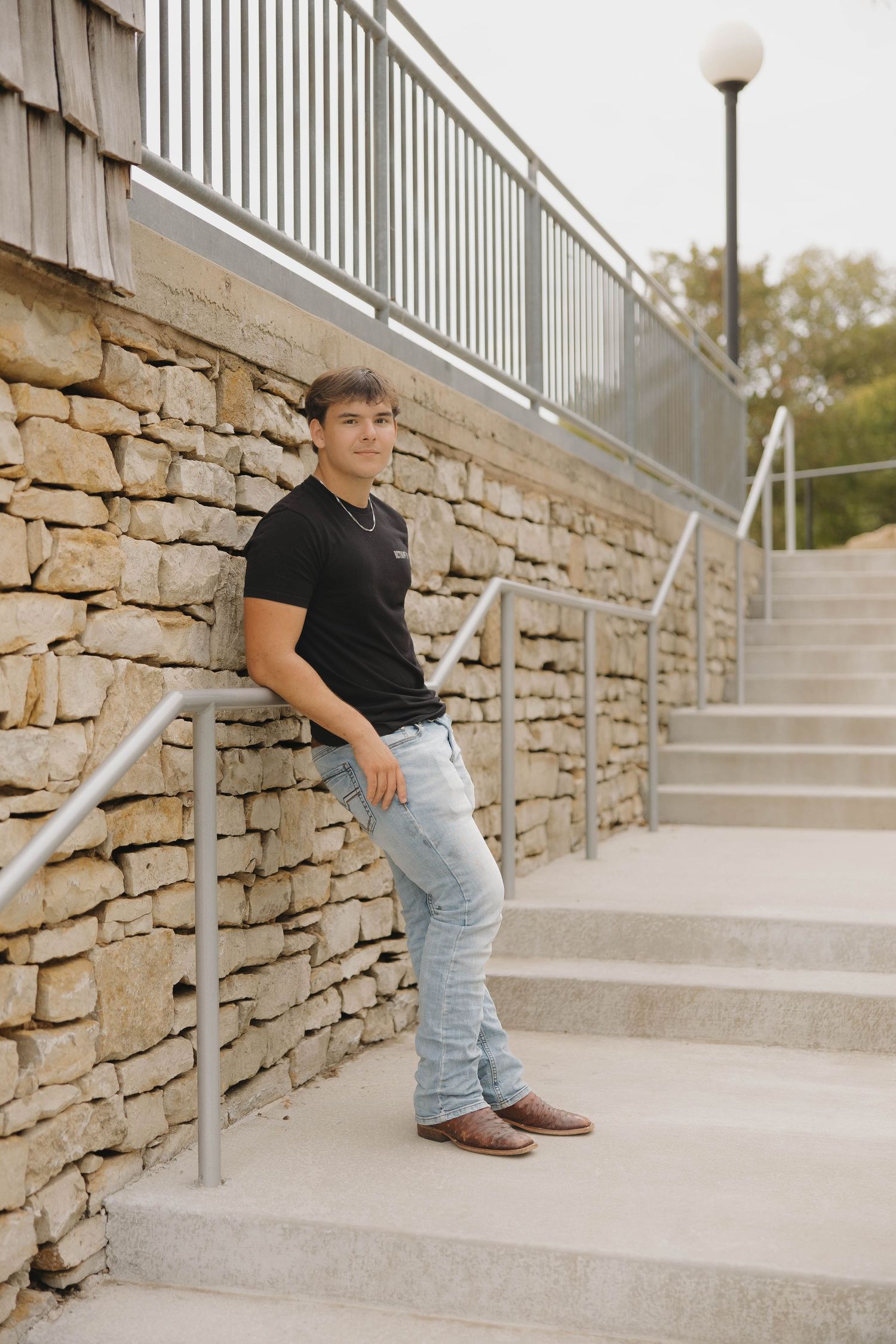 A series of four outdoor portraits showing someone sitting on concrete steps against a rustic stone wall.