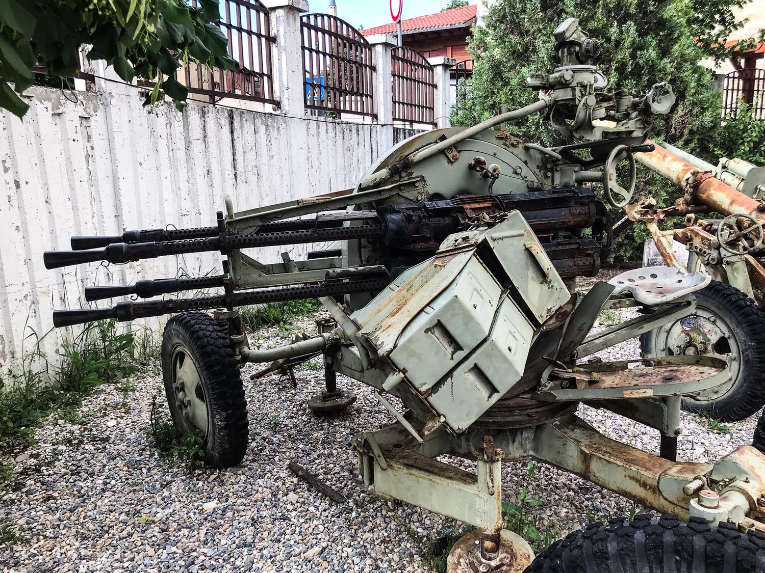 Vintage military artillery guns displayed in an outdoor museum setting with gravel ground and trees in background.