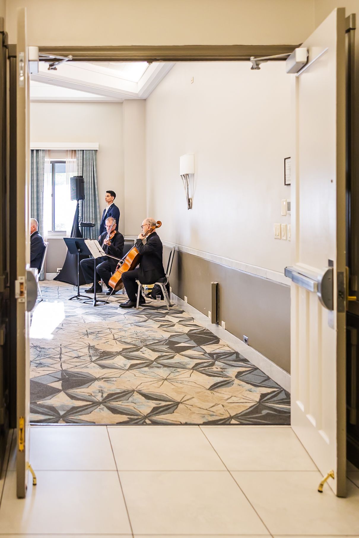 Musicians practice in a modern room with geometric patterned carpet and bright white walls.