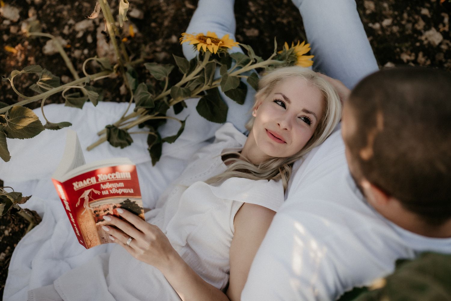 Couple sharing snacks and enjoying a romantic moment in a sunlit field at sunset.