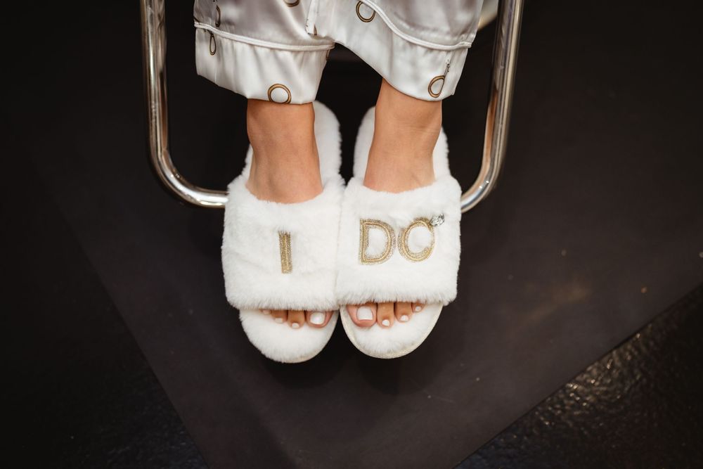 White fluffy slippers with decorative embellishments sit against a dark background.
