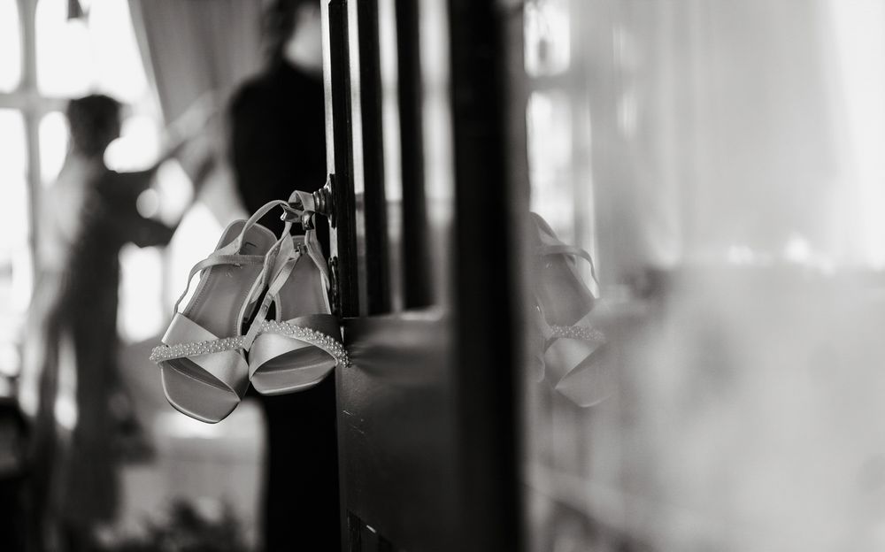 A pair of wedding bells hangs in soft focus against a blurred black and white background.