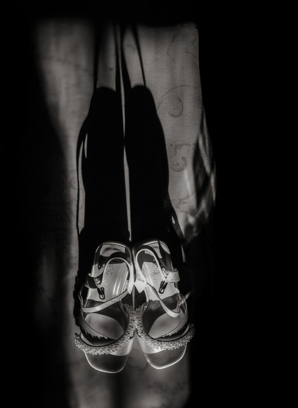 A sequence of black and white photos showing elegant bridal shoes with sparkly details casting dramatic shadows.