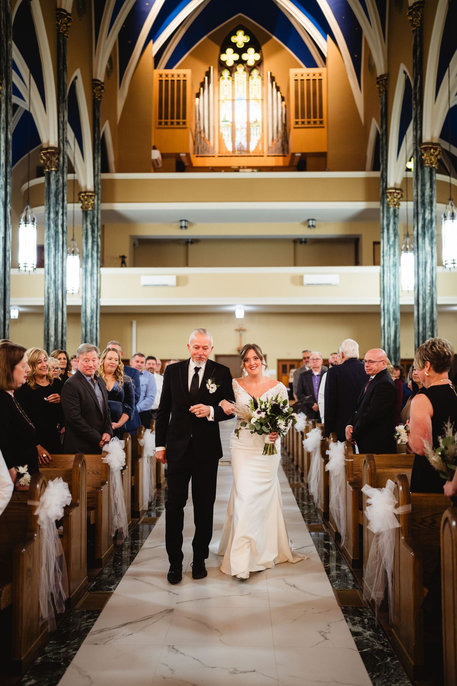 A wedding ceremony processional sequence showing the bride walking down the aisle of a beautiful church with vaulted ceilings.