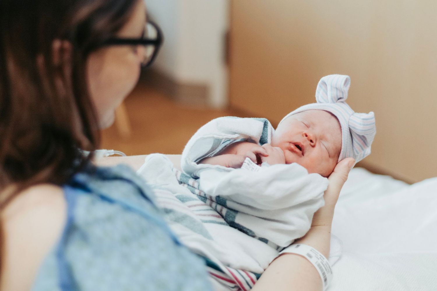 A newborn baby in her mothers arms in her hospital bed