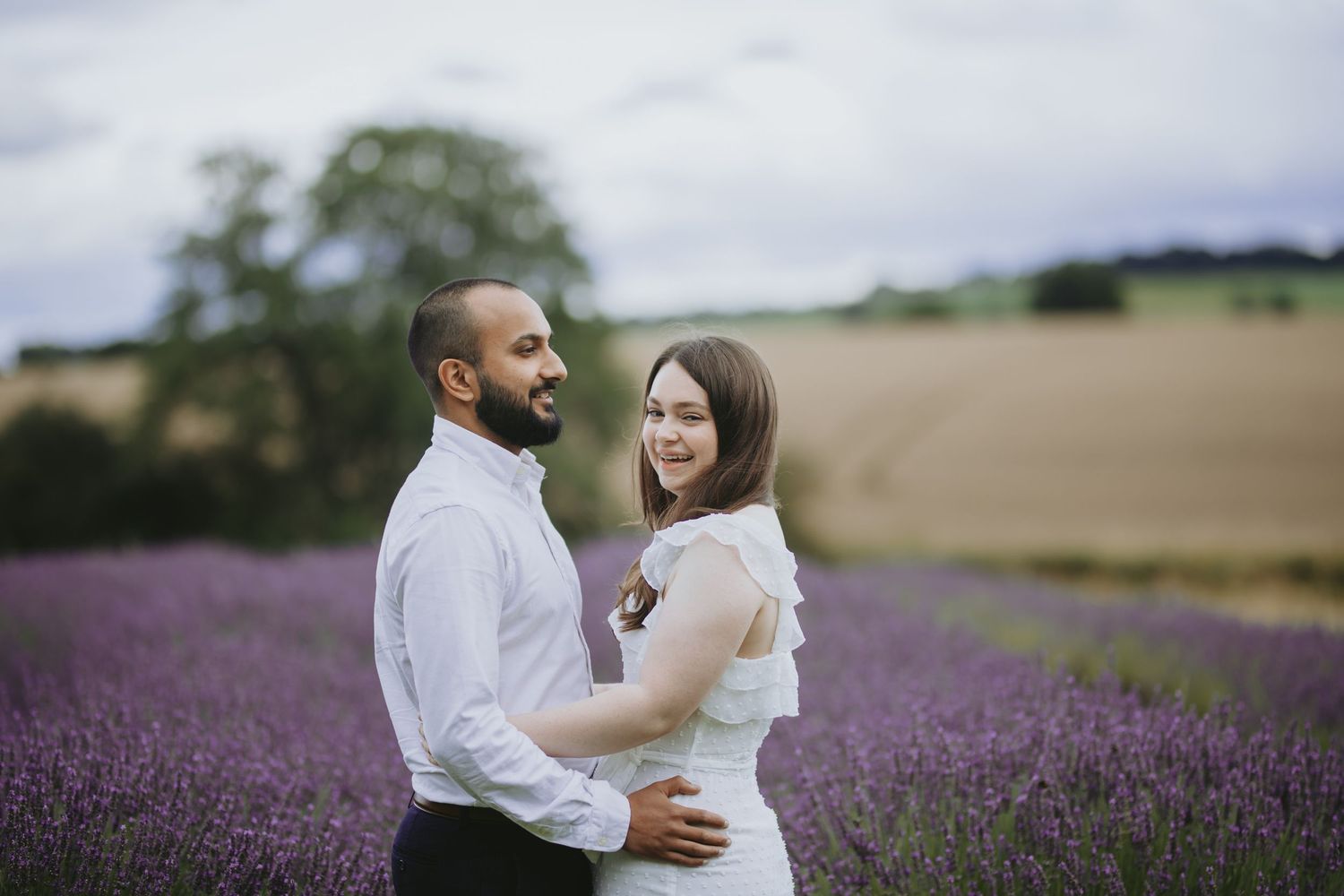 A couple shares an intimate moment in a blooming lavender field on a summer day.
