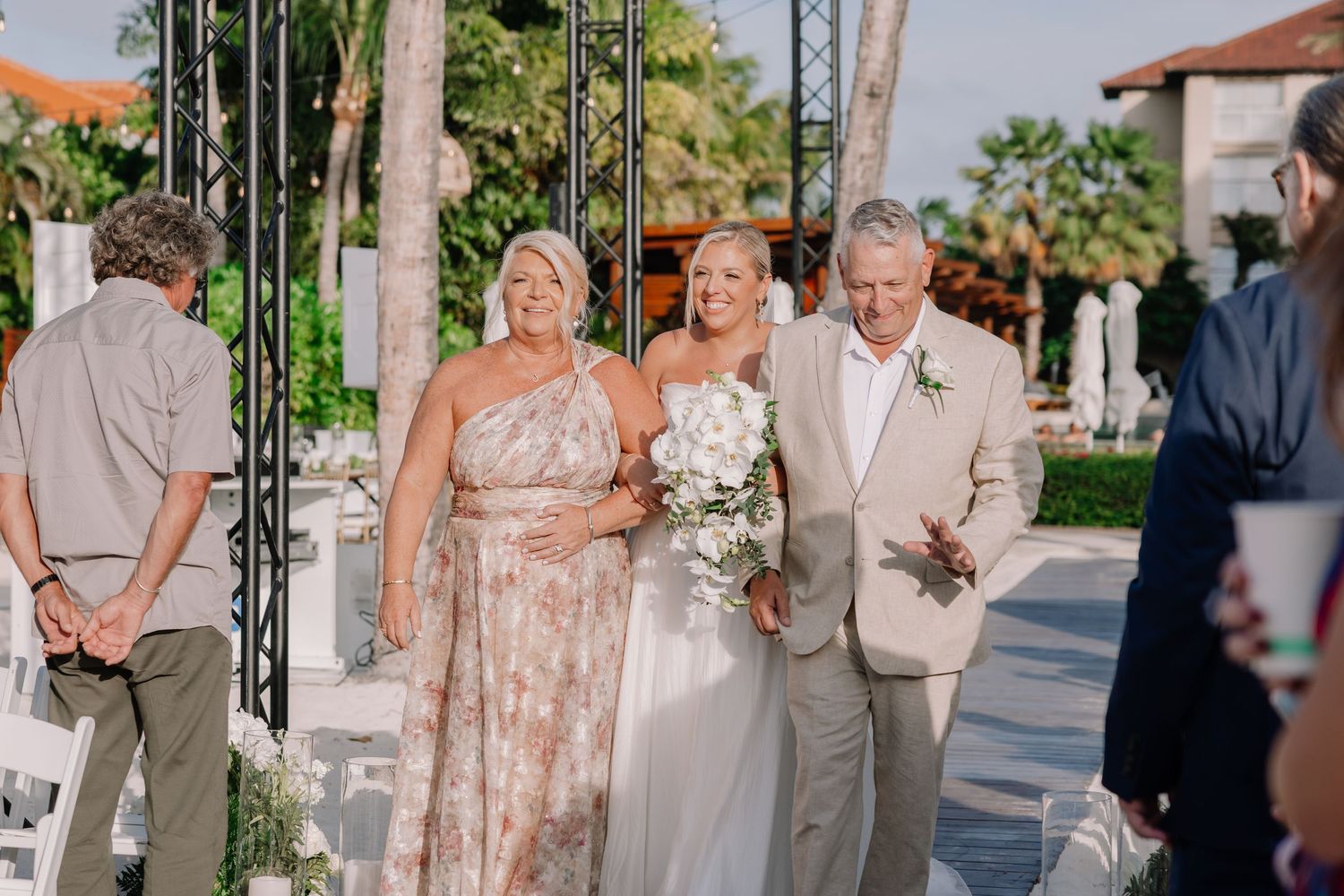 Wedding party in tan and blush attire posing together on a sunny outdoor patio.