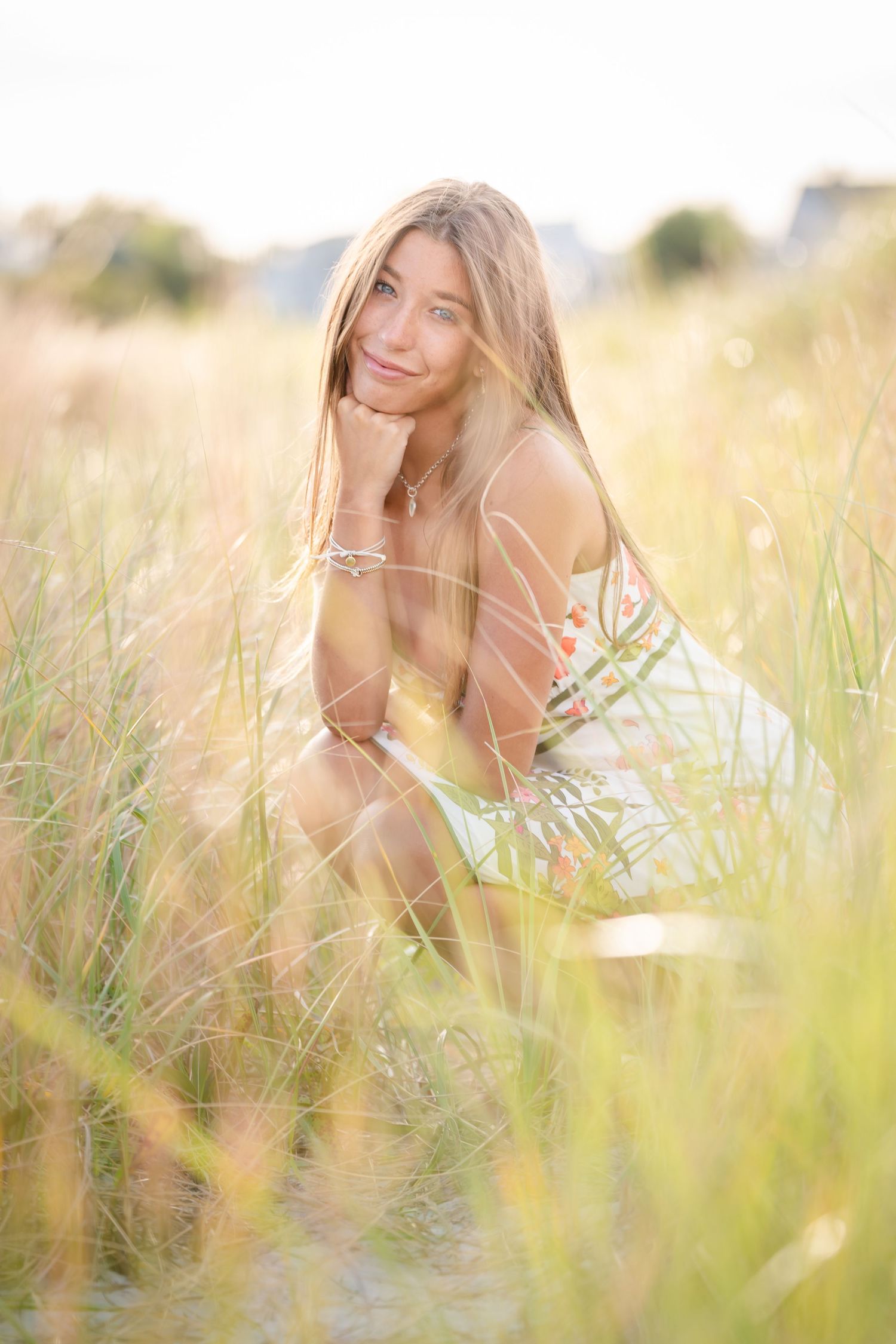 A white dress stands out against golden grass and evergreen trees in dreamy sunlit meadow.