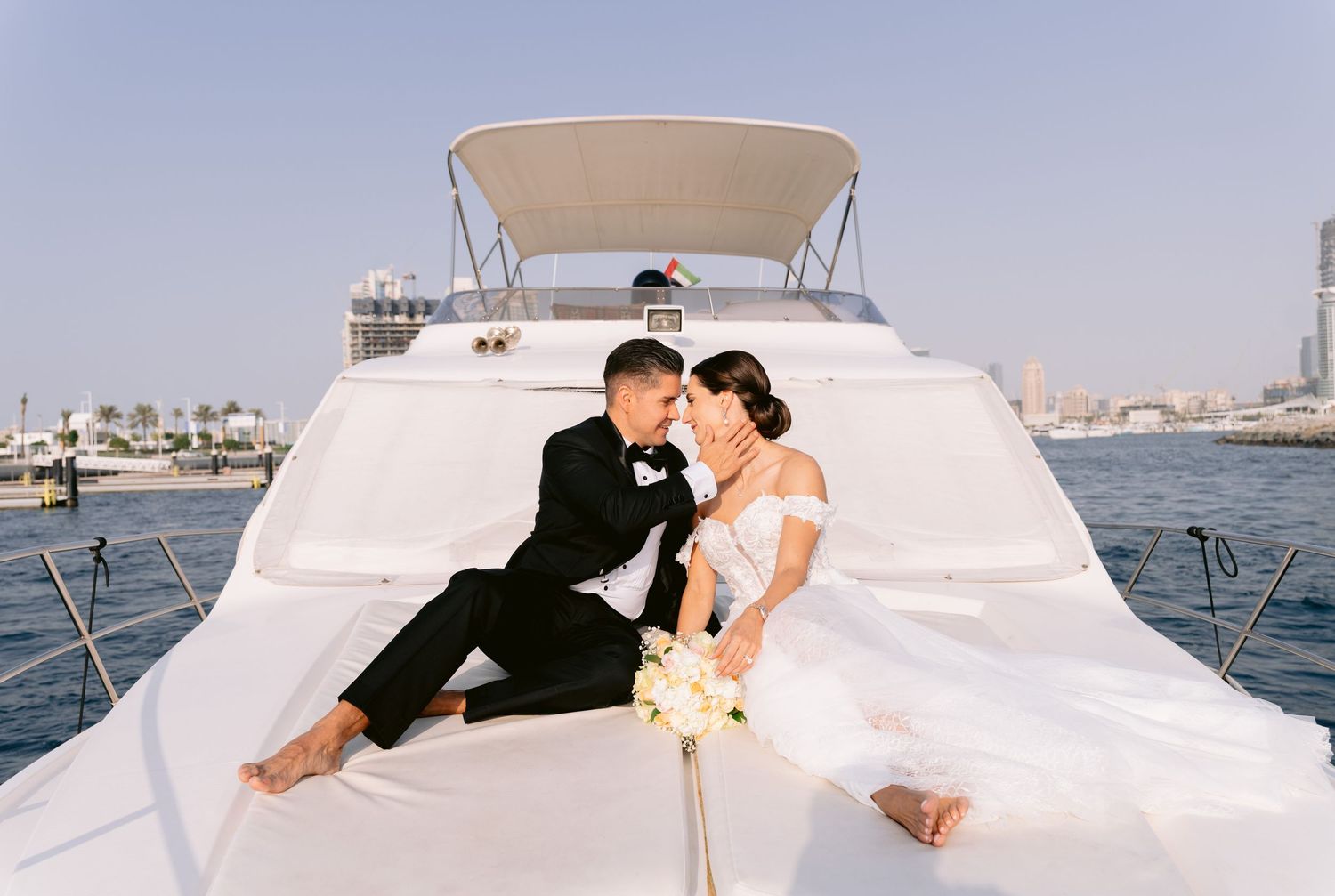 Couple sharing romantic moments aboard a luxury yacht on a sunny day at sea.