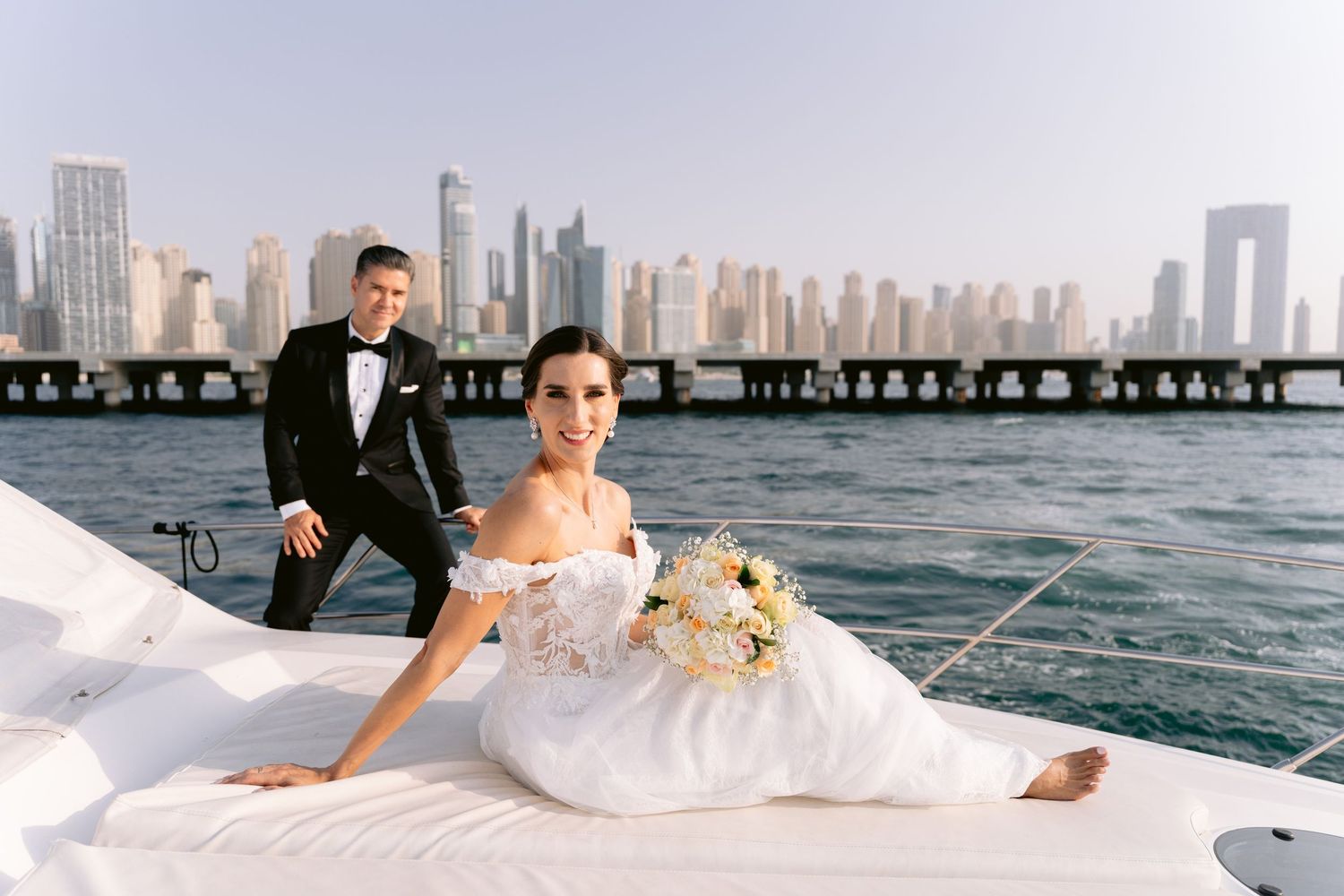 A wedding couple poses along the Miami waterfront with the downtown skyline visible in the background.