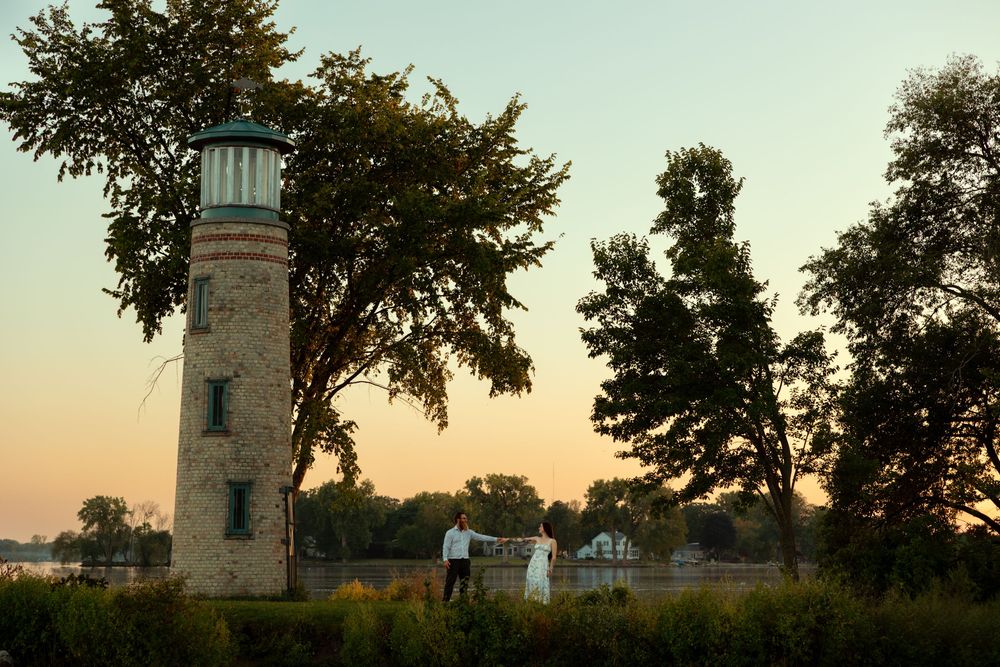 Lighthouse tower with white buildings and trees silhouetted against a sunset sky at Concord Point in Maryland.