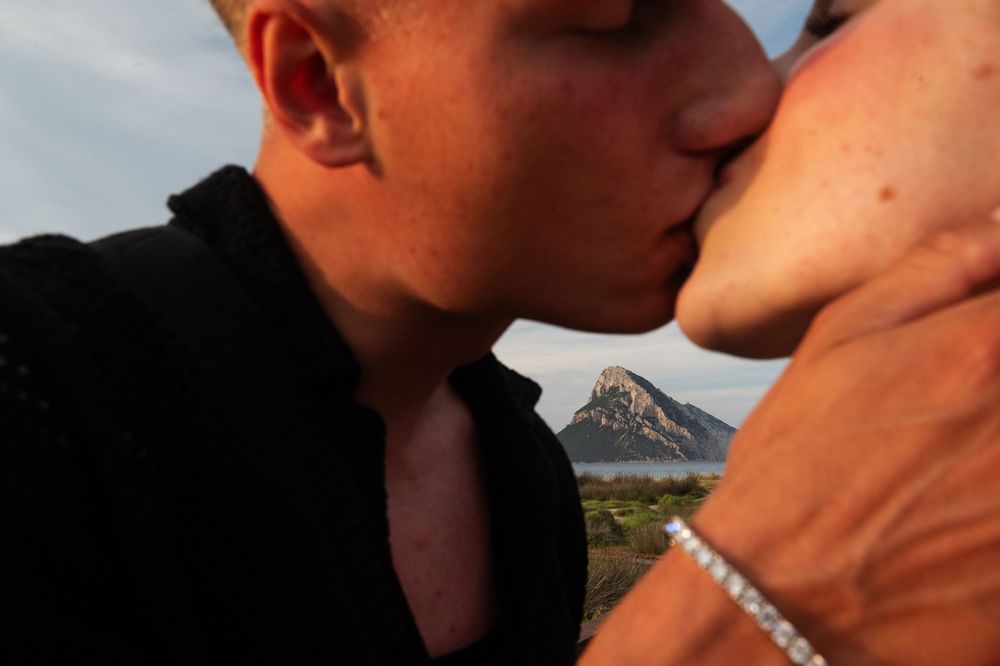 A romantic couple sharing an intimate moment on a wooden boardwalk with dramatic lighting.
