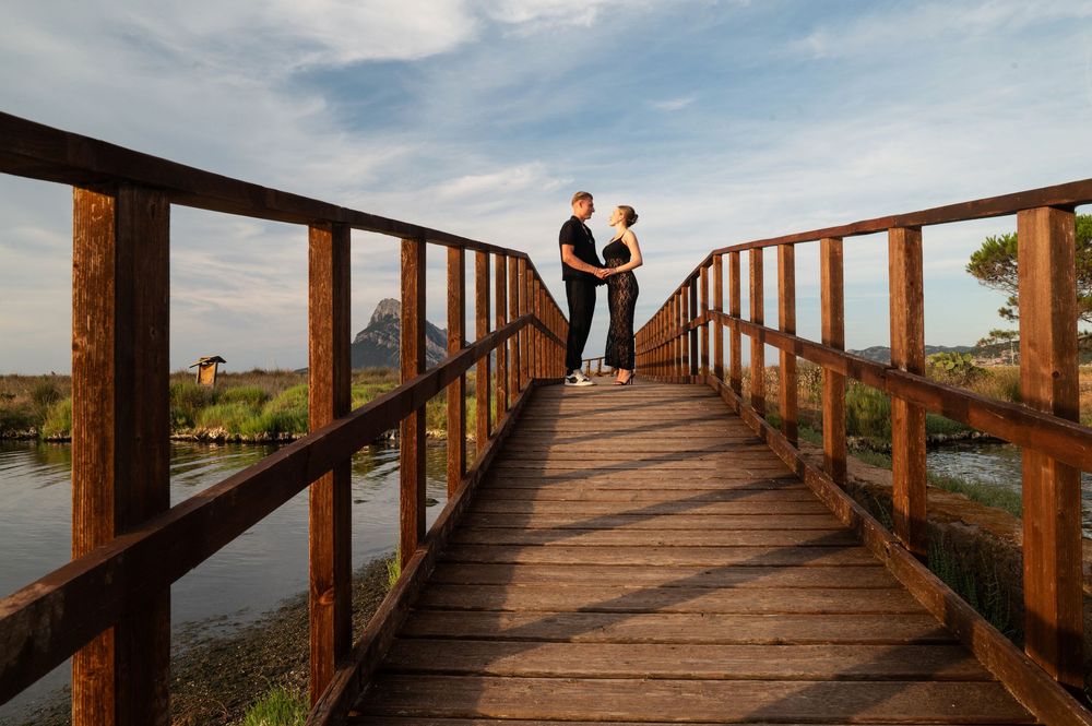 Long wooden boardwalk stretches into the distance with a couple at the end.