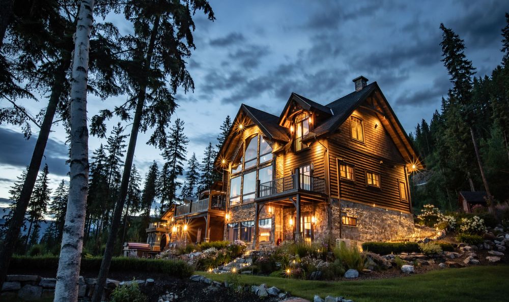 Luxury mountain home exterior at dusk with warm lighting — professional real estate photography in Revelstoke.