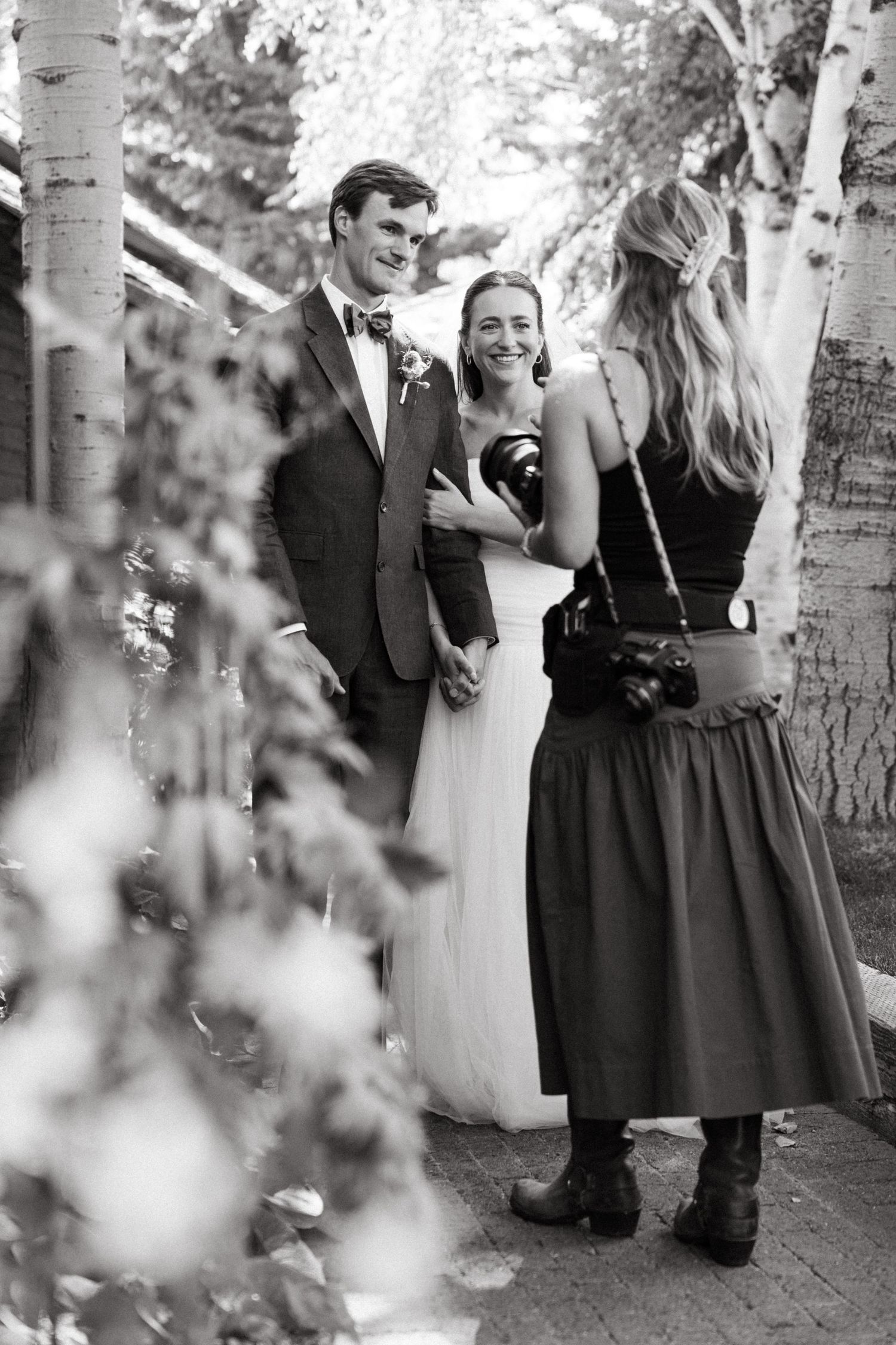Black and white wedding party photo series showing candid moments between guests during outdoor celebration.