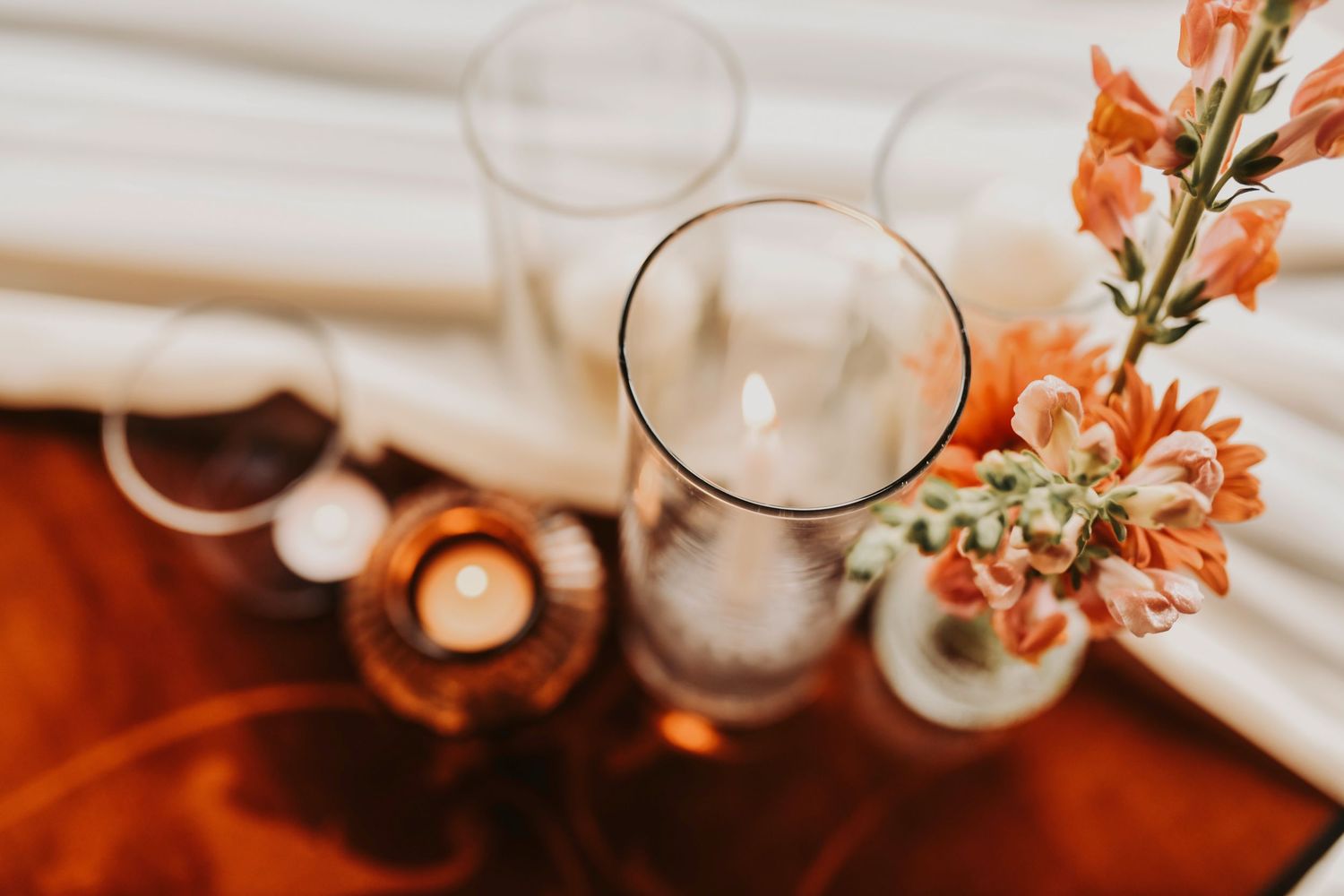 a collection of glass votives with ivory candles inside for a wedding center pieces