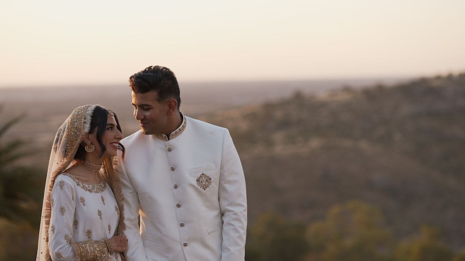 Couple walking together in a romantic outdoor setting with mountains in the background.