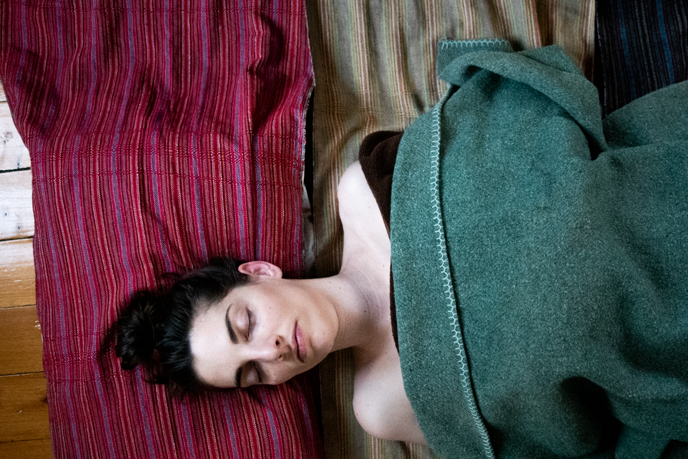 Person lying on a couch with striped pink and red cushions in a relaxed pose.