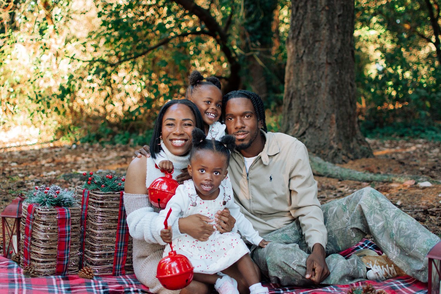 Family sitting on a plaid blanket surrounded by rustic Christmas props in Kent, Washington.