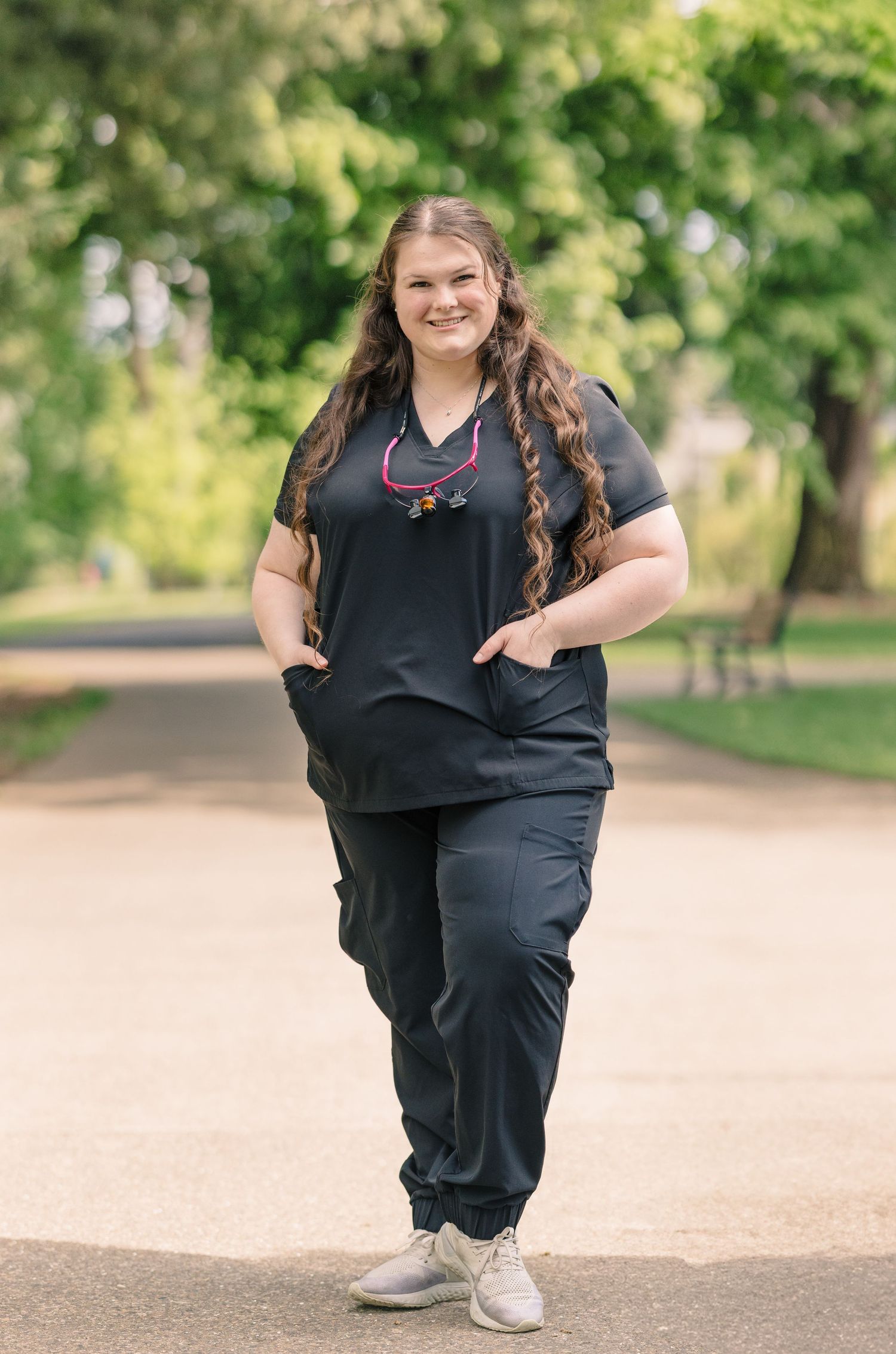 Portrait session on a tree-lined path wearing dark clothing.