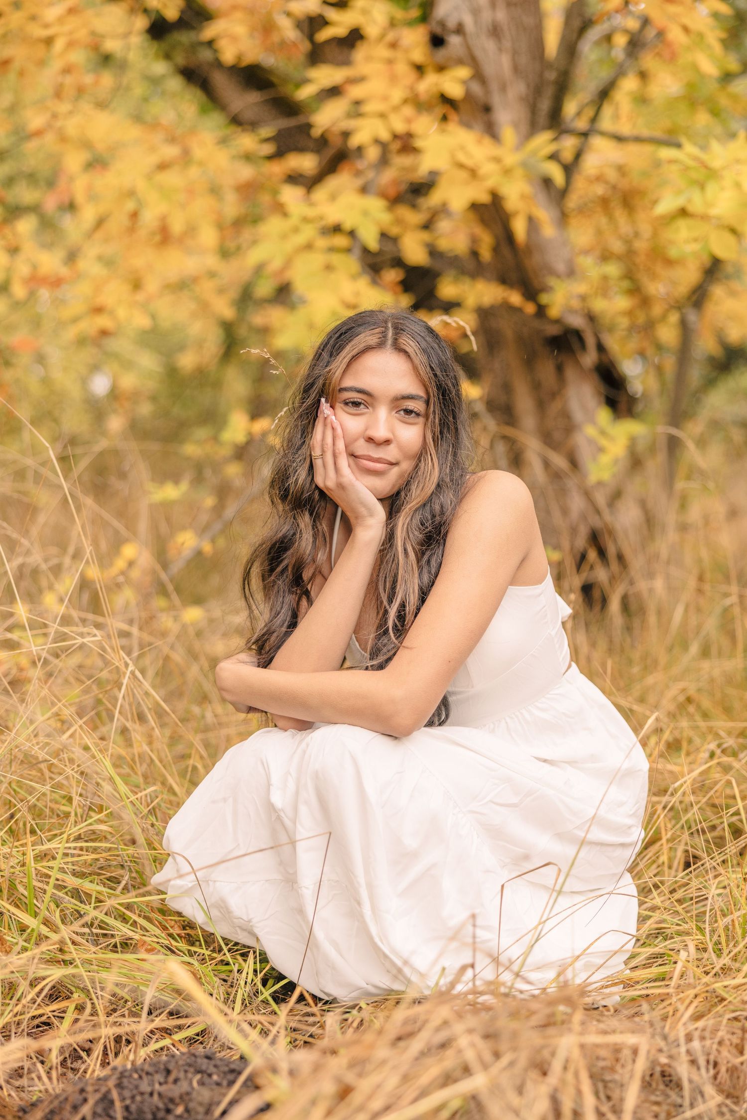 Person in white dress lying in golden autumn grass during sunset.