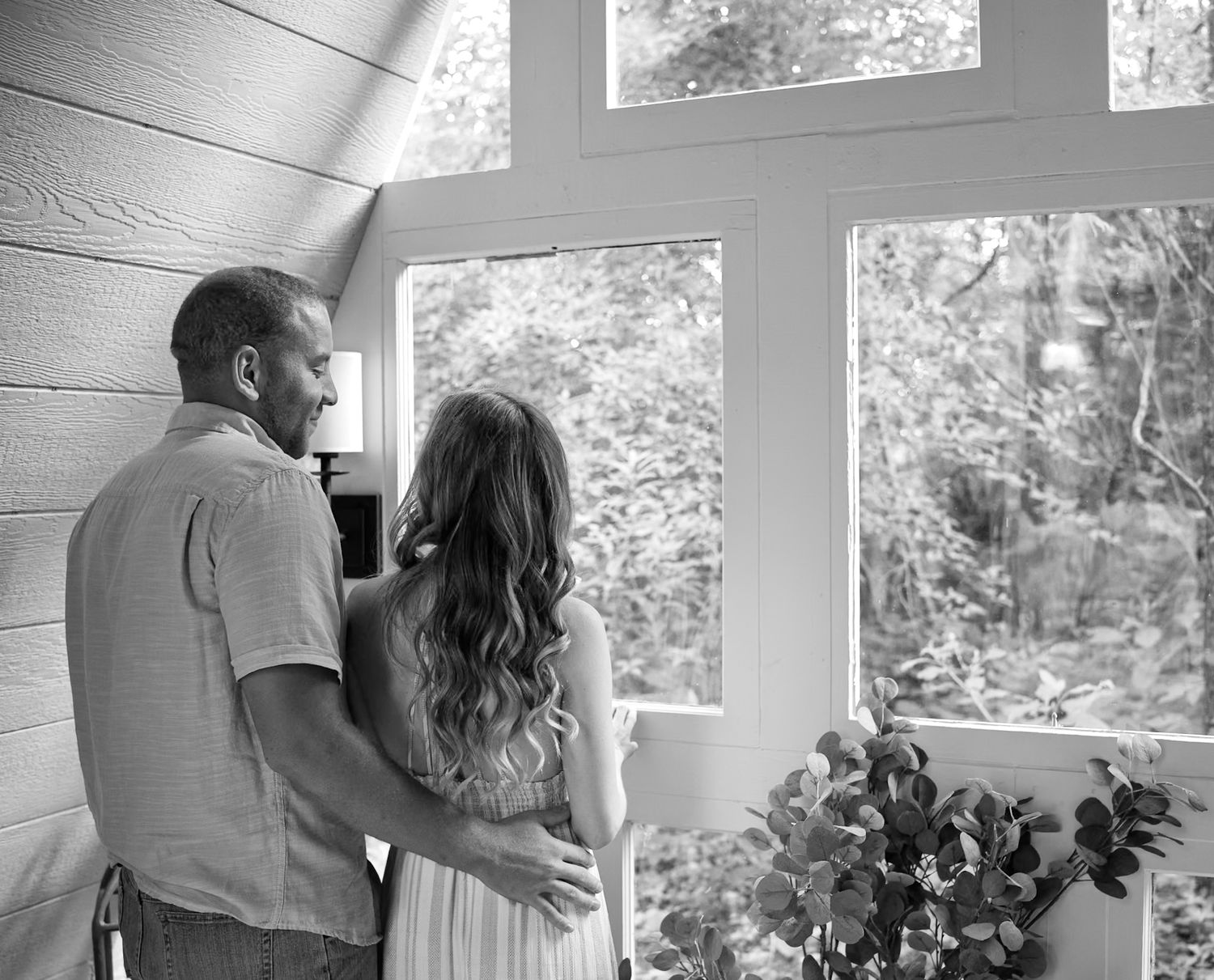 Silhouetted couple standing by large windows in a bright interior space.