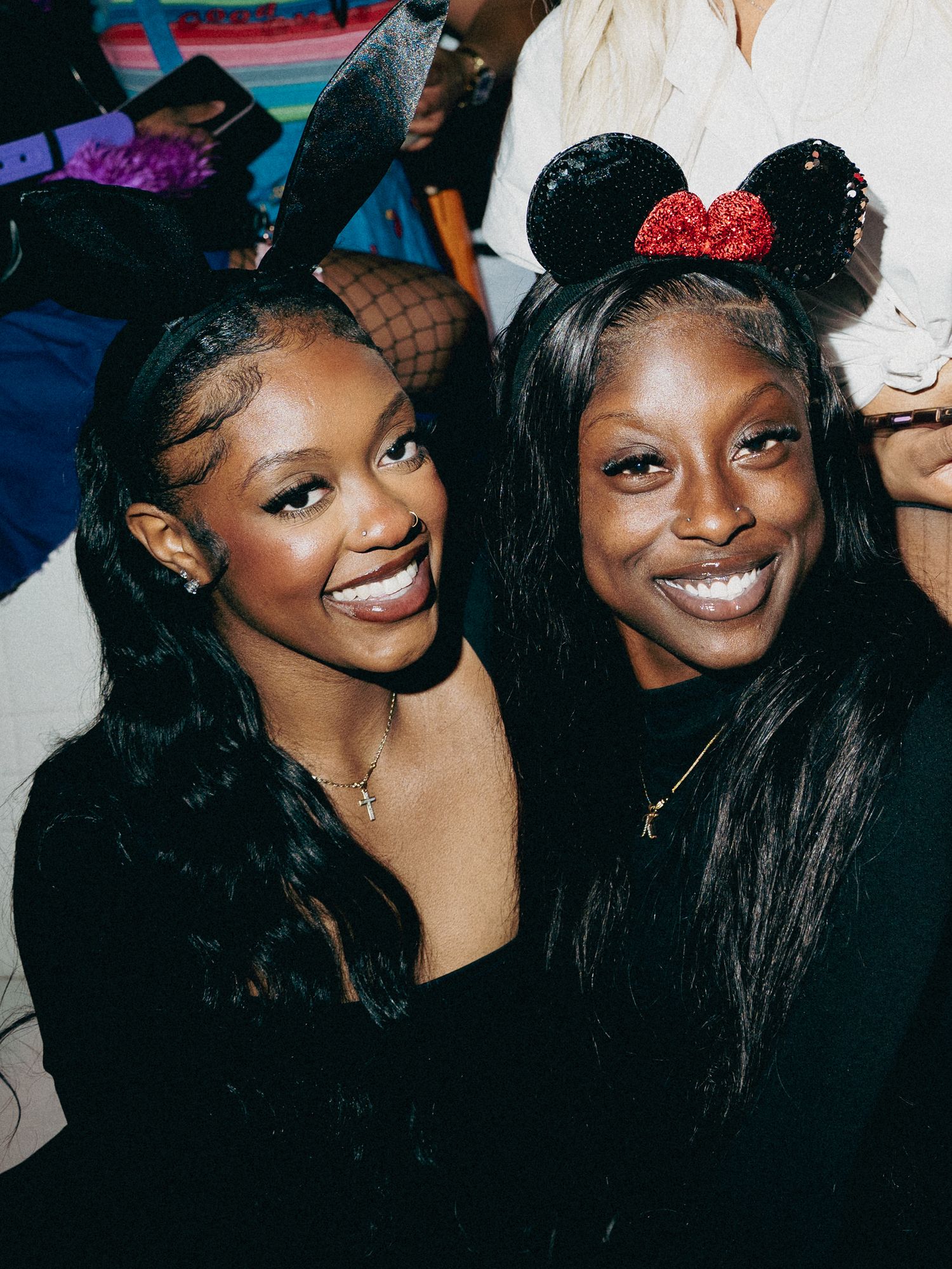 Two friends enjoying a party together, with one wearing sparkly Minnie Mouse ears at a festive gathering.